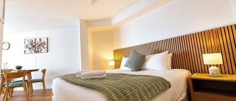 A hotel room with a bed, a desk, a chair, a lamp, and a ceiling fan.