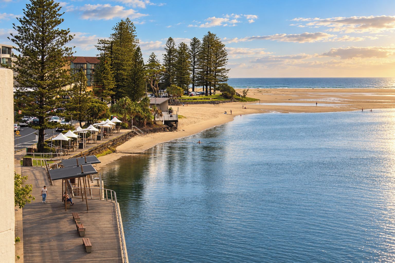 A waterfront property with a wooden deck, outdoor seating, and a view of the beach and ocean.