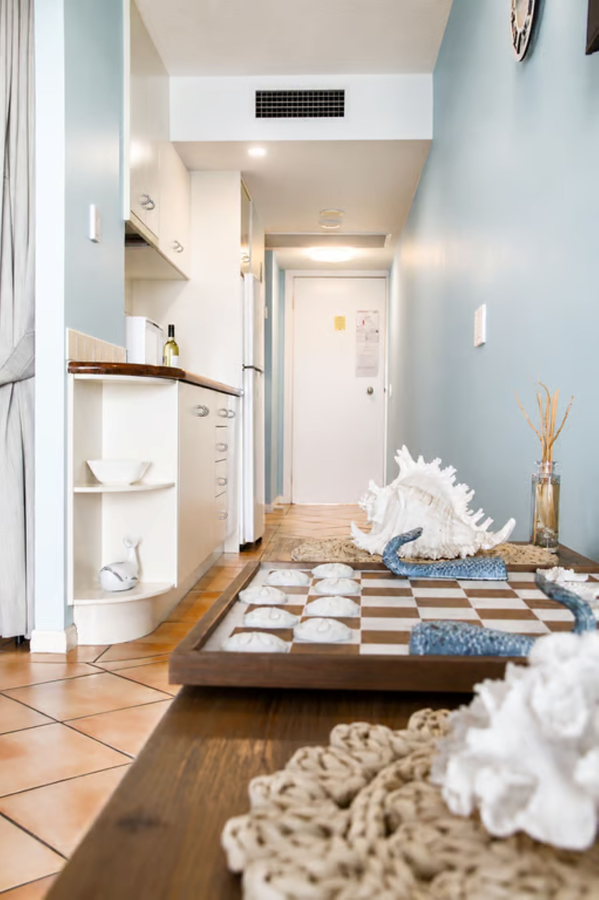 A kitchen with white cabinets, a wooden countertop, and a checkered tray with decorative items.