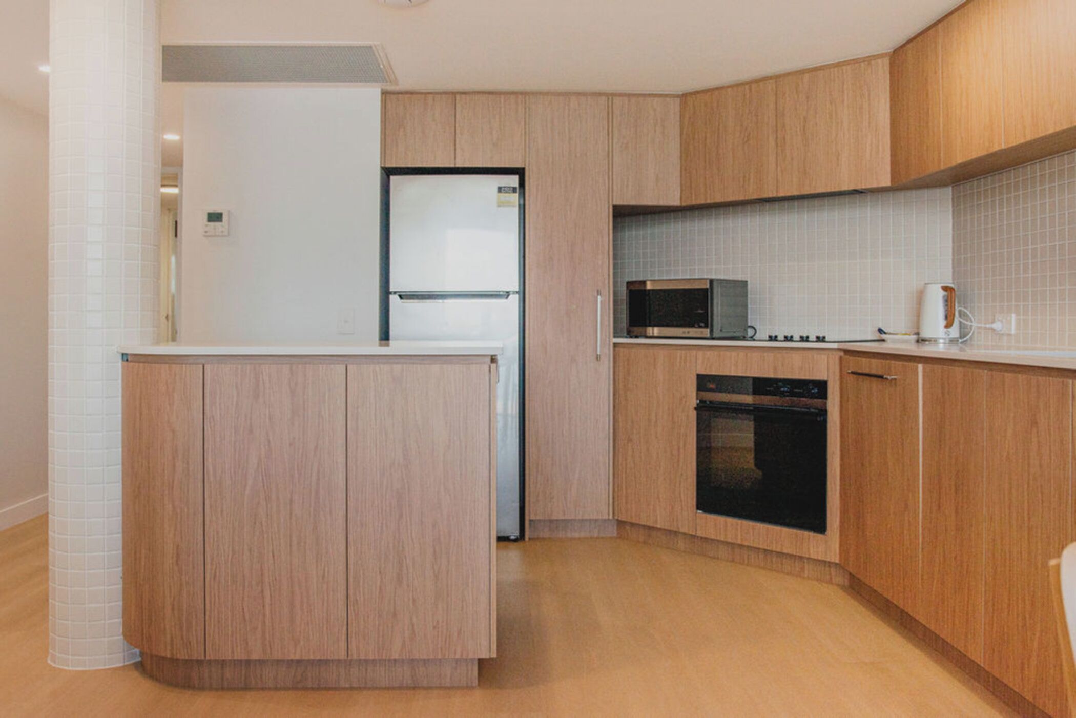 A modern kitchen with wooden cabinets, a microwave, an oven, and a dishwasher.