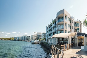 Un hotel frente al agua con balcones, mobiliario exterior y vistas al mar.