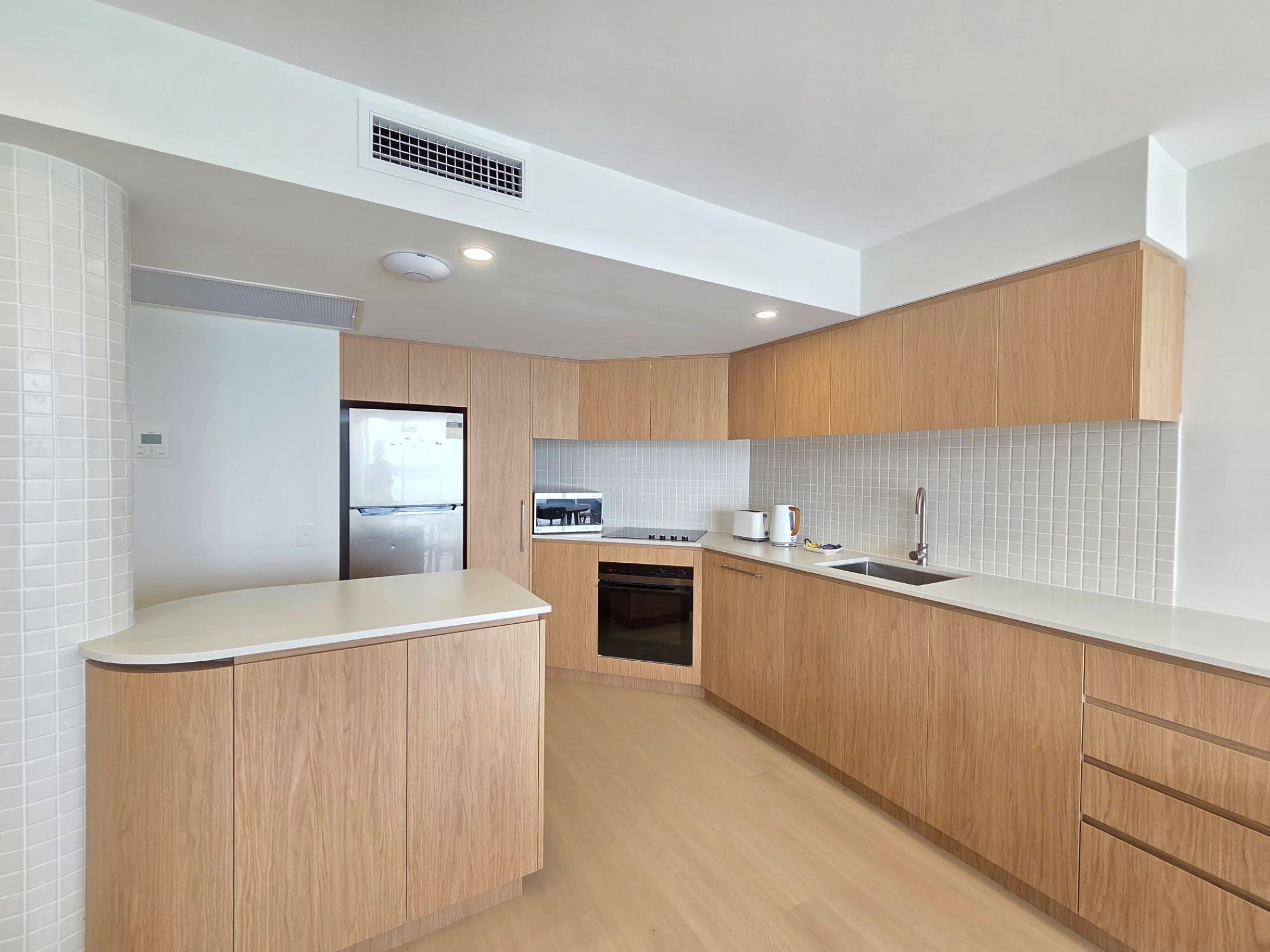 Eine moderne Küche mit Holzausstattung, Backofen, Spüle und Geschirrspüler.