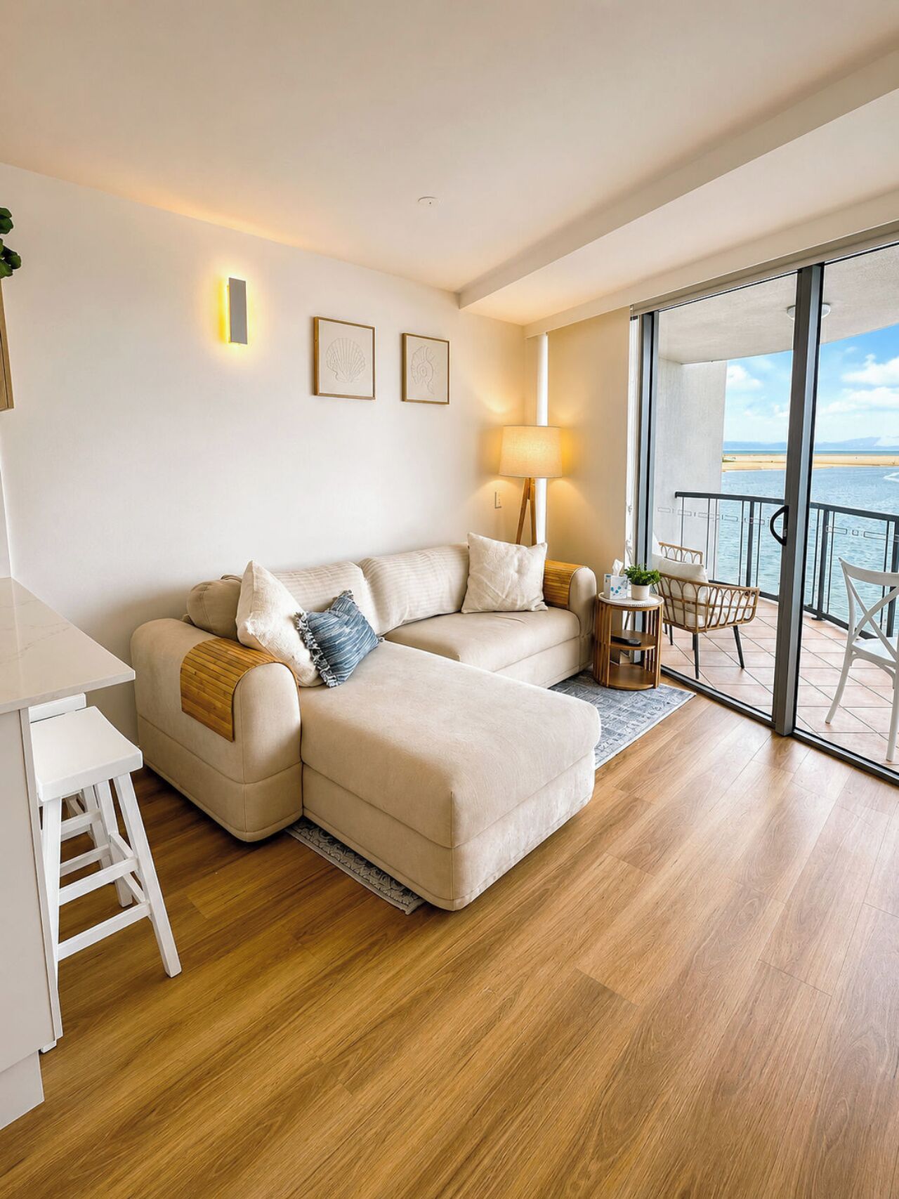 Una sala moderna con un sofá, una mesita y una silla. Cuenta con un balcón y vistas al mar.
