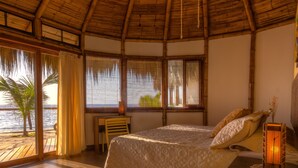 Ein Zimmer mit Bett, Schreibtisch und Blick auf den Strand.