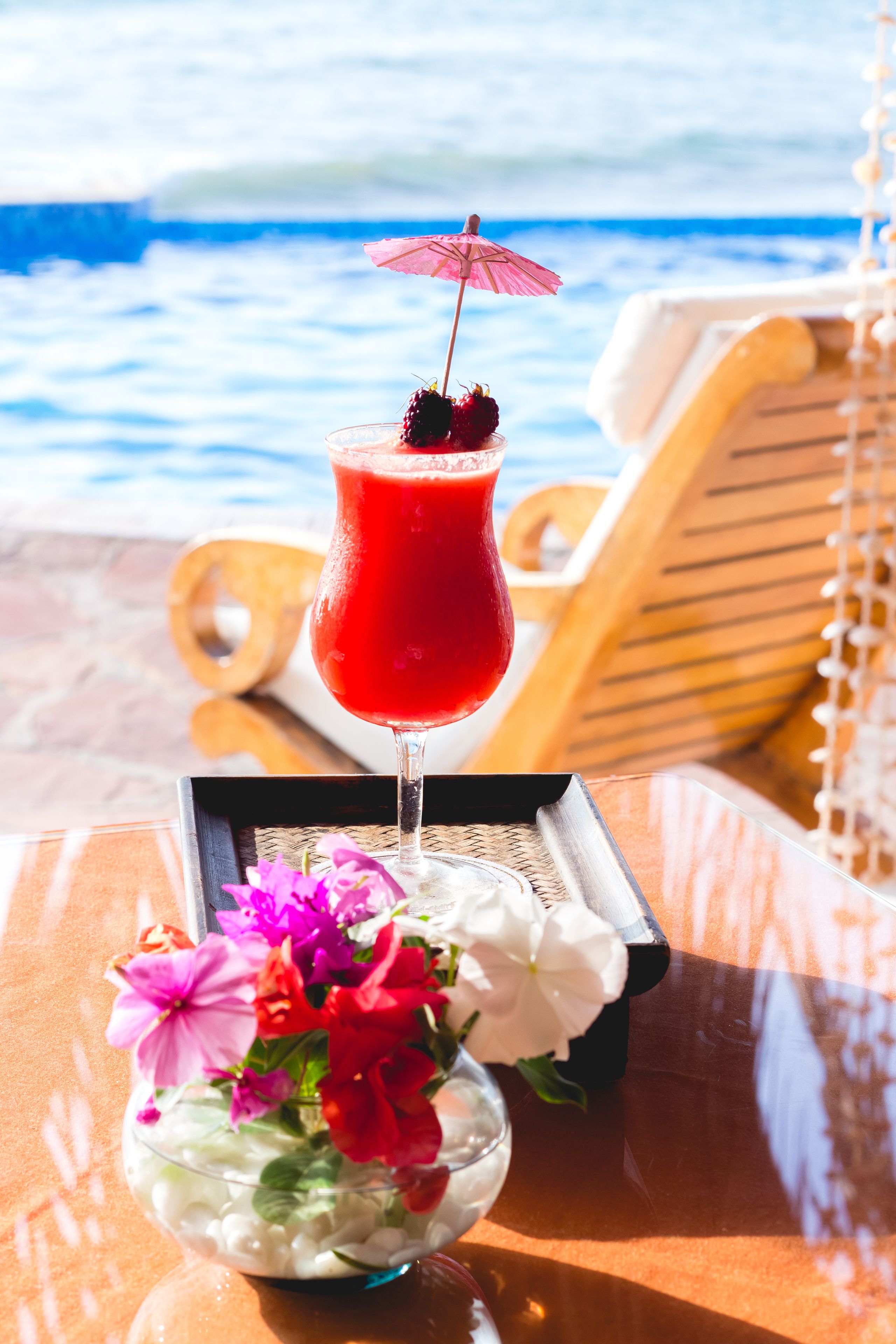 A cocktail on a tray with a beach view in the background.