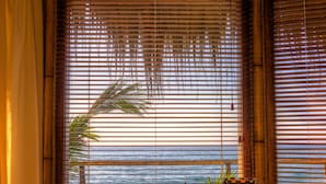 Ein Zimmer mit einem Holztisch, einem Stuhl und einem Fenster mit Bambusrollos.