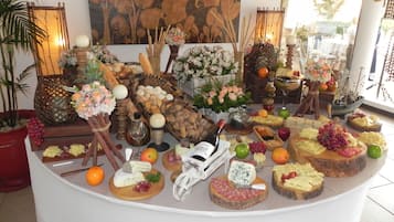 A buffet table with various cheeses, fruits, and bread.
