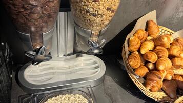 Un bufé de desayuno con cereales, granola y pastelería.