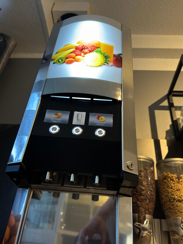 Una cafetera con una exhibición de frutas y diversas opciones de bebidas.