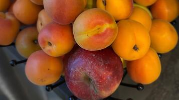 Un frutero con melocotones y manzanas.