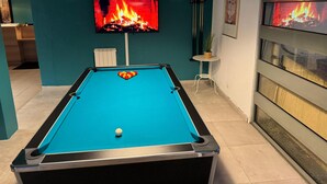 A pool table with balls, a television displaying a fire, and a framed picture on the wall. - Hôtel L'ESCALE d'Alès (Ales)