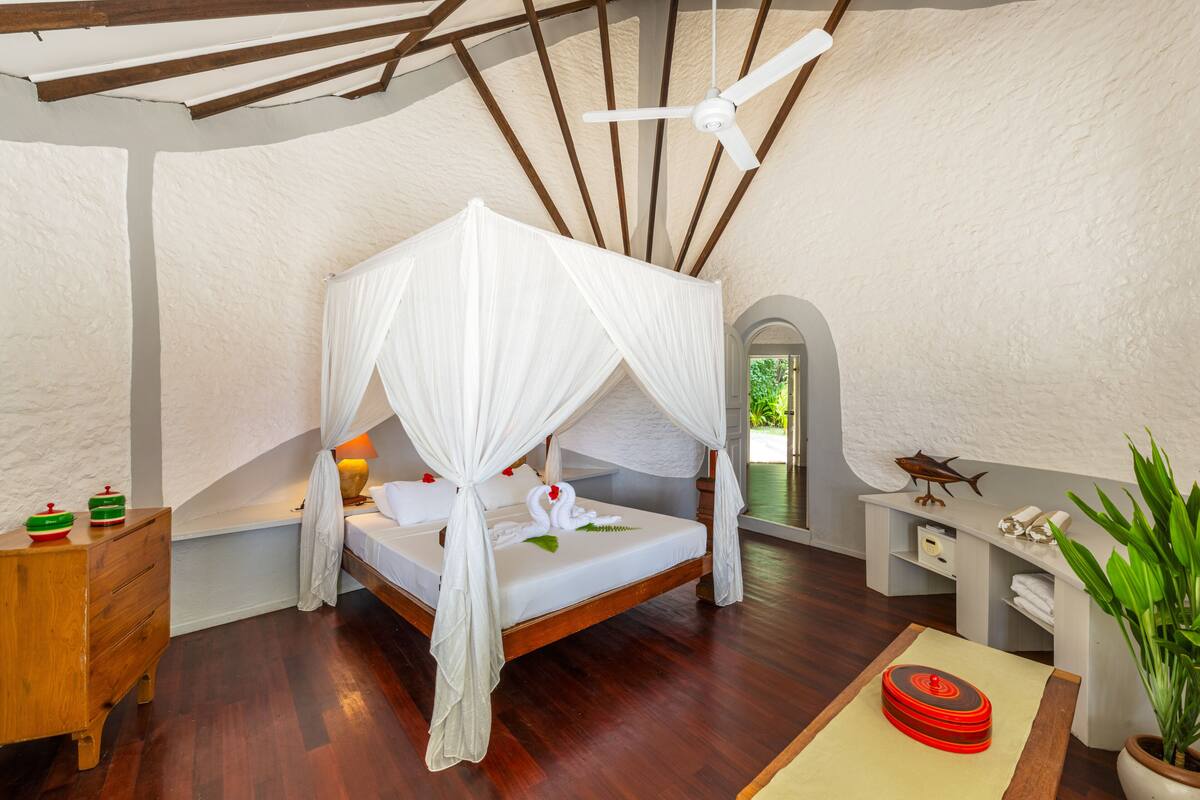 Une chambre à coucher avec un lit à baldaquin, des meubles en bois et un ventilateur de plafond.