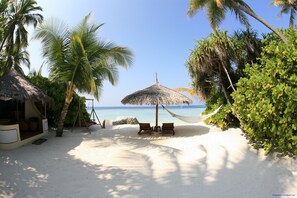 På stranden, hvit sand, parasoller og strandhåndklær