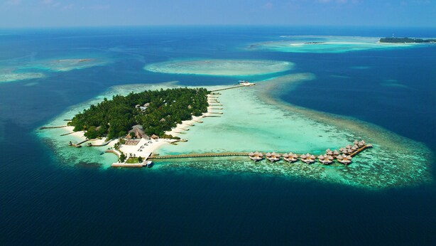 An aerial view of a tropical island resort with a long pier connecting to overwater bungalows. - Nika Island Resort & Spa (Kudafolhudhoo)