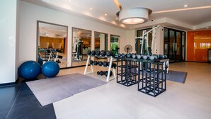 A modern gym with exercise equipment, large windows, and a clean, spacious layout. - Hotel J Residence (Pattaya)