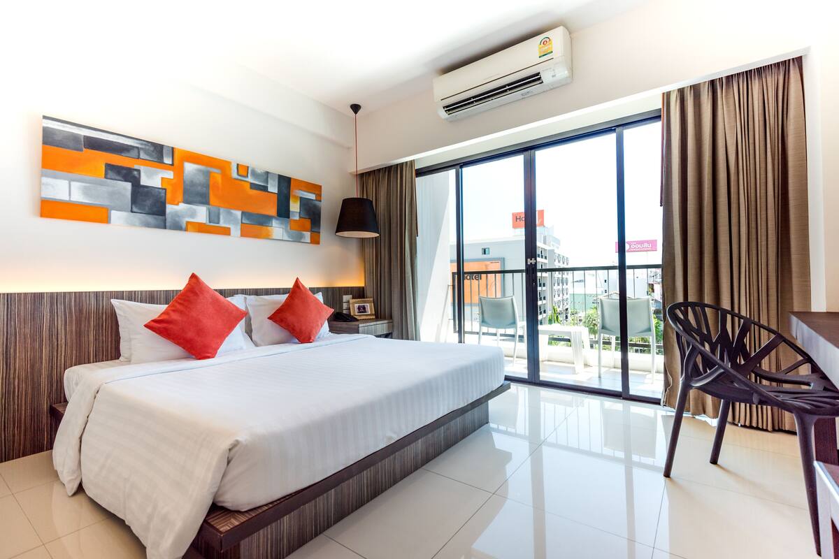A hotel room with a large bed, a desk, and a view of the outside.