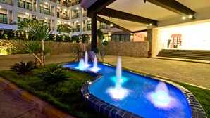 A hotel courtyard with a swimming pool, fountains, and a covered walkway. - Hotel J Residence (Pattaya)