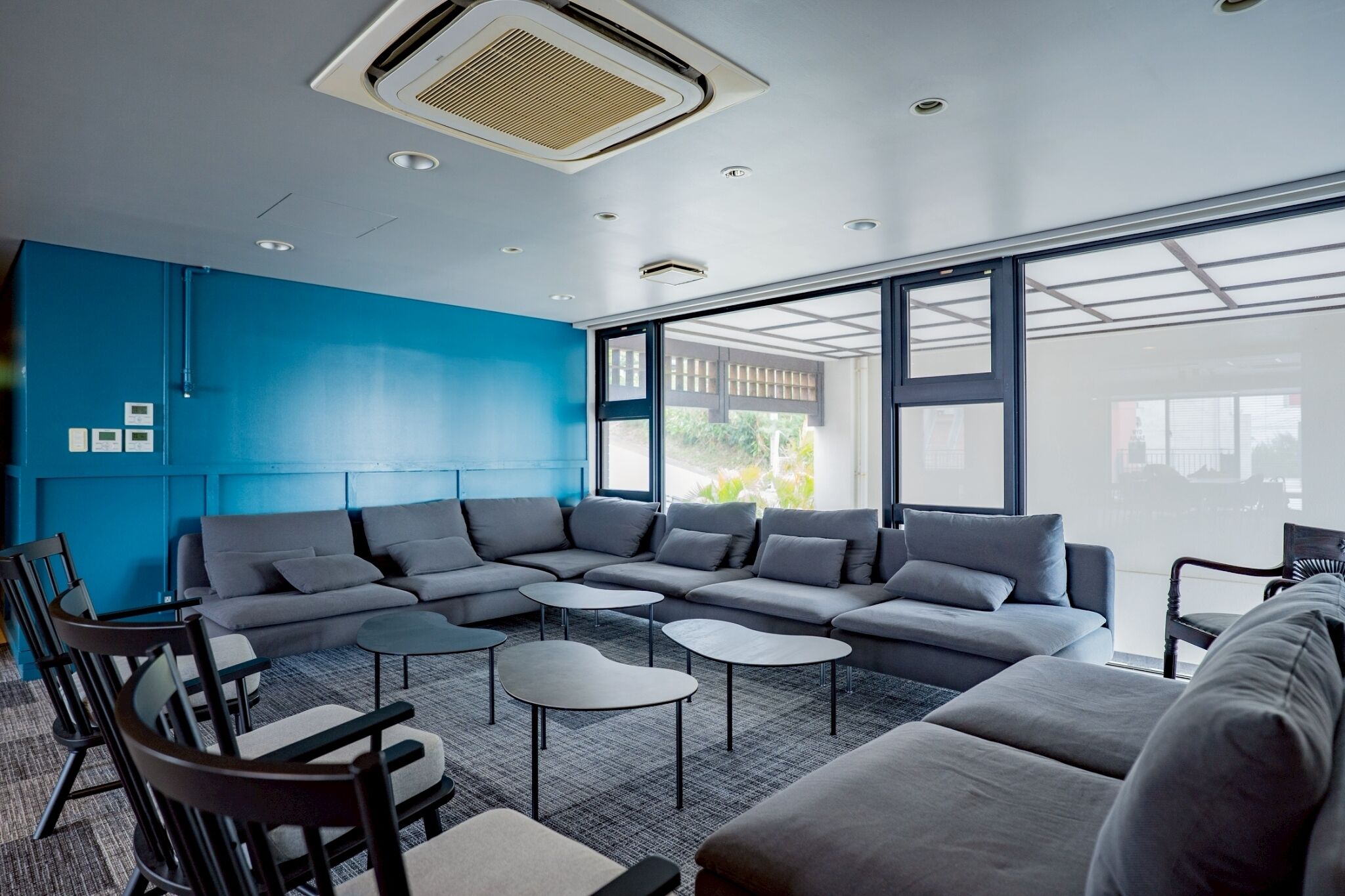 A modern lounge area with a sectional sofa, round coffee tables, and a blue accent wall.