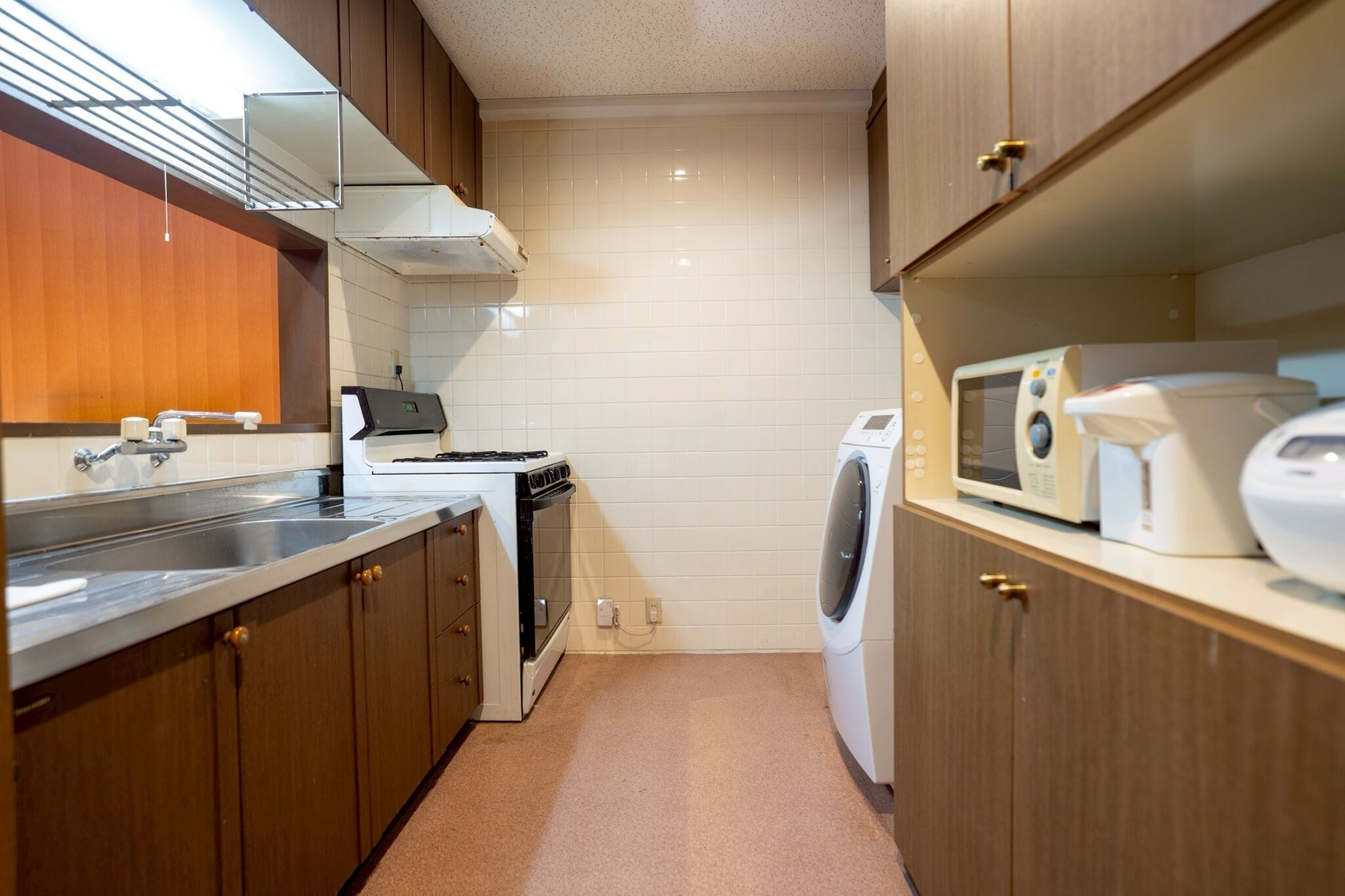 A compact kitchen with a stove, microwave, and washing machine.
