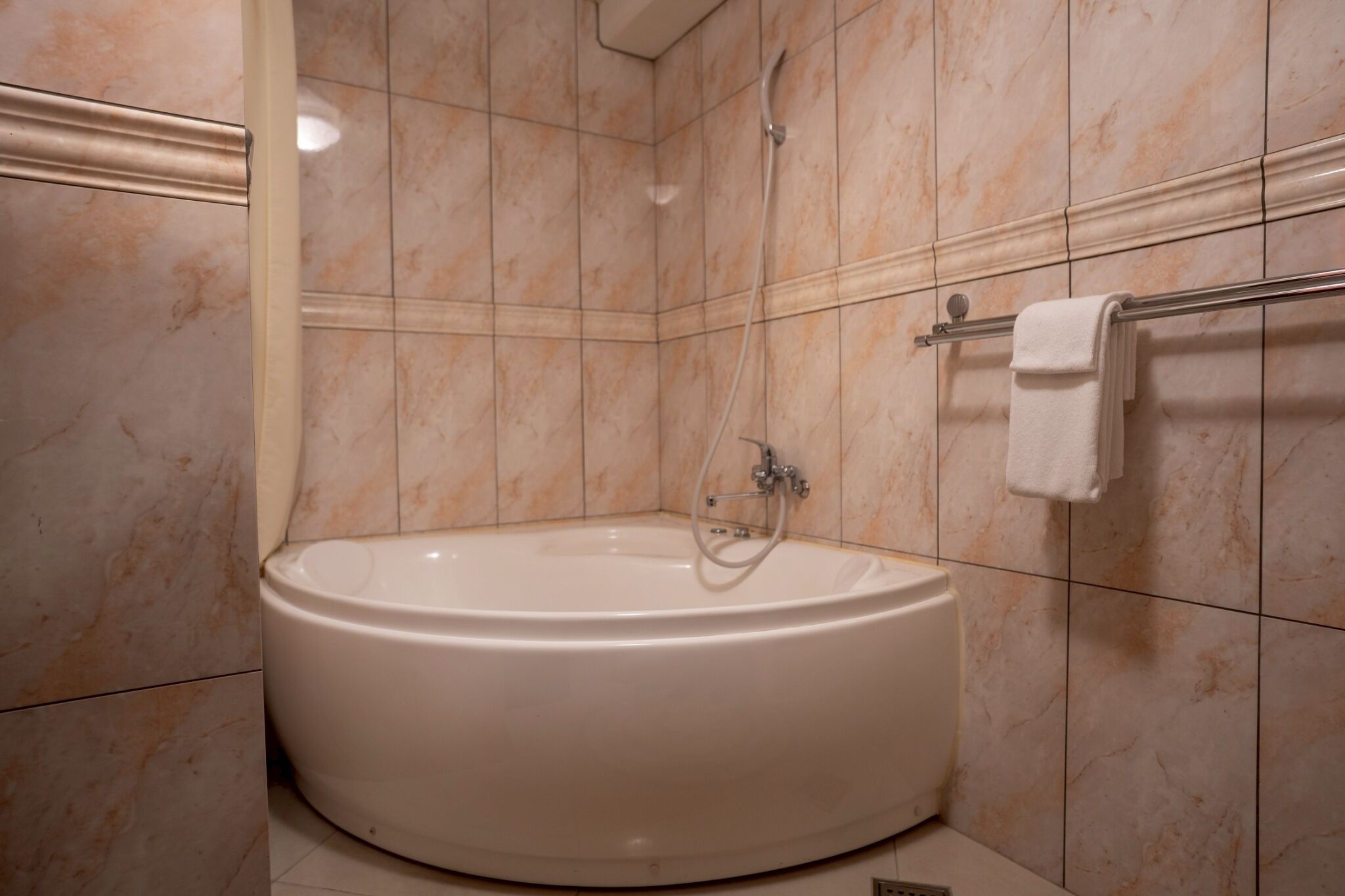 A bathroom with a freestanding bathtub, a towel rack, and tiled walls.