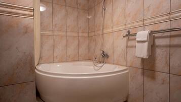A bathroom with a freestanding bathtub, a towel rack, and tiled walls.