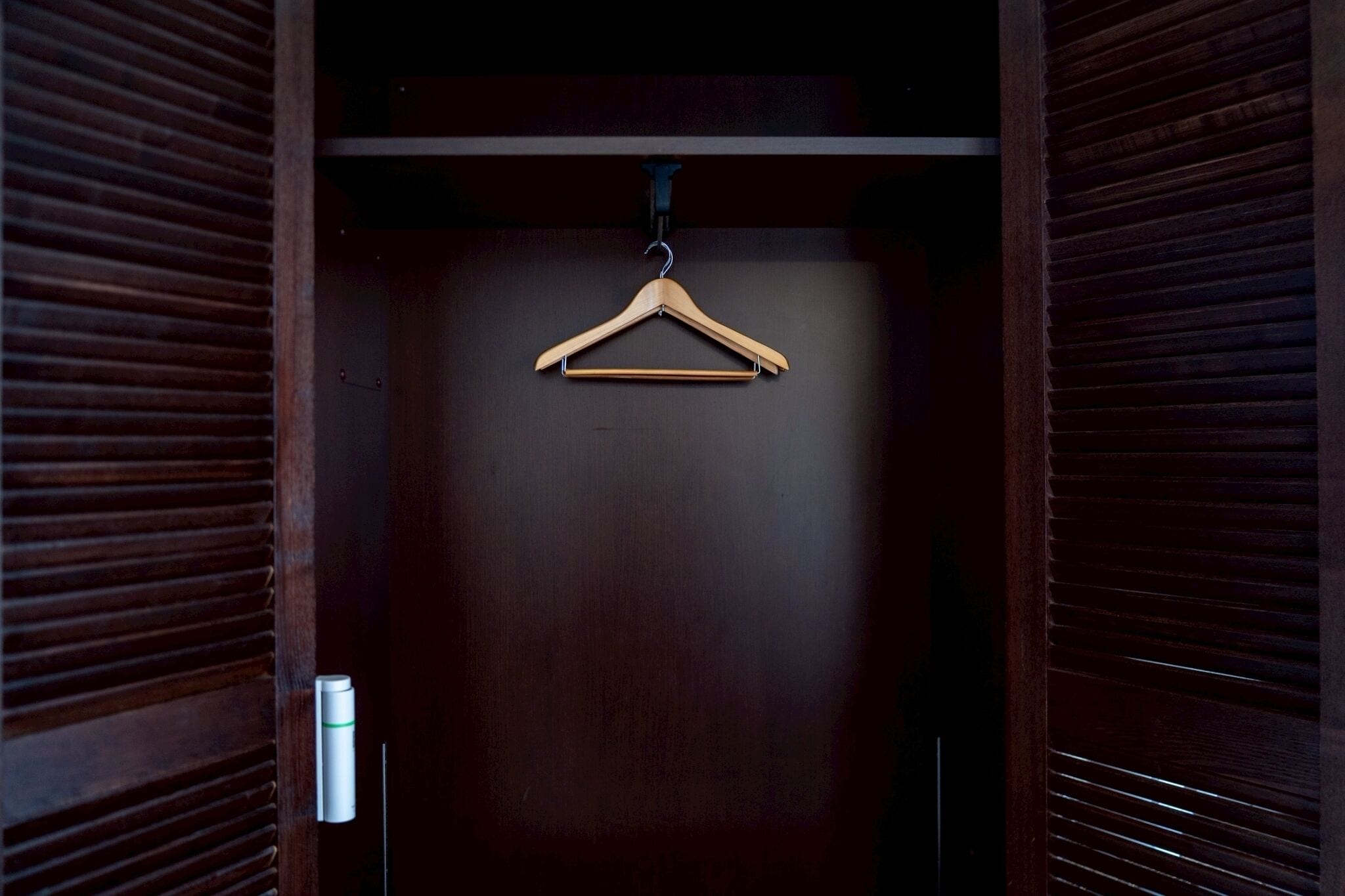 Una porta d'armadio in legno con un appendiabiti in legno appeso a un gancio.