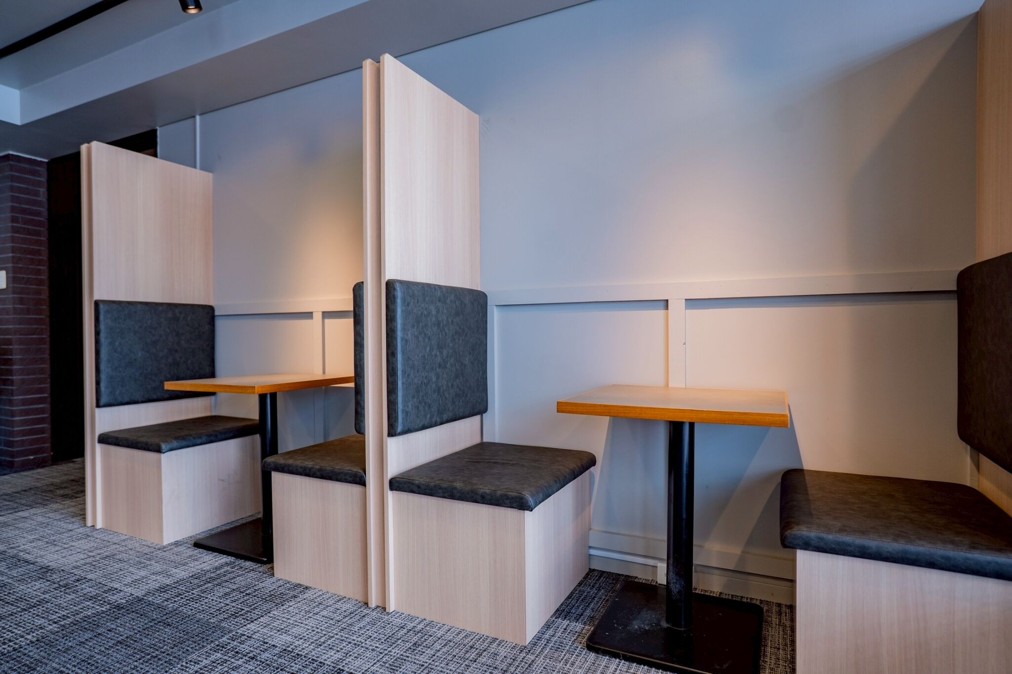 Un espacio de oficina moderno con cubículos, cada uno con un escritorio y un asiento acolchado.