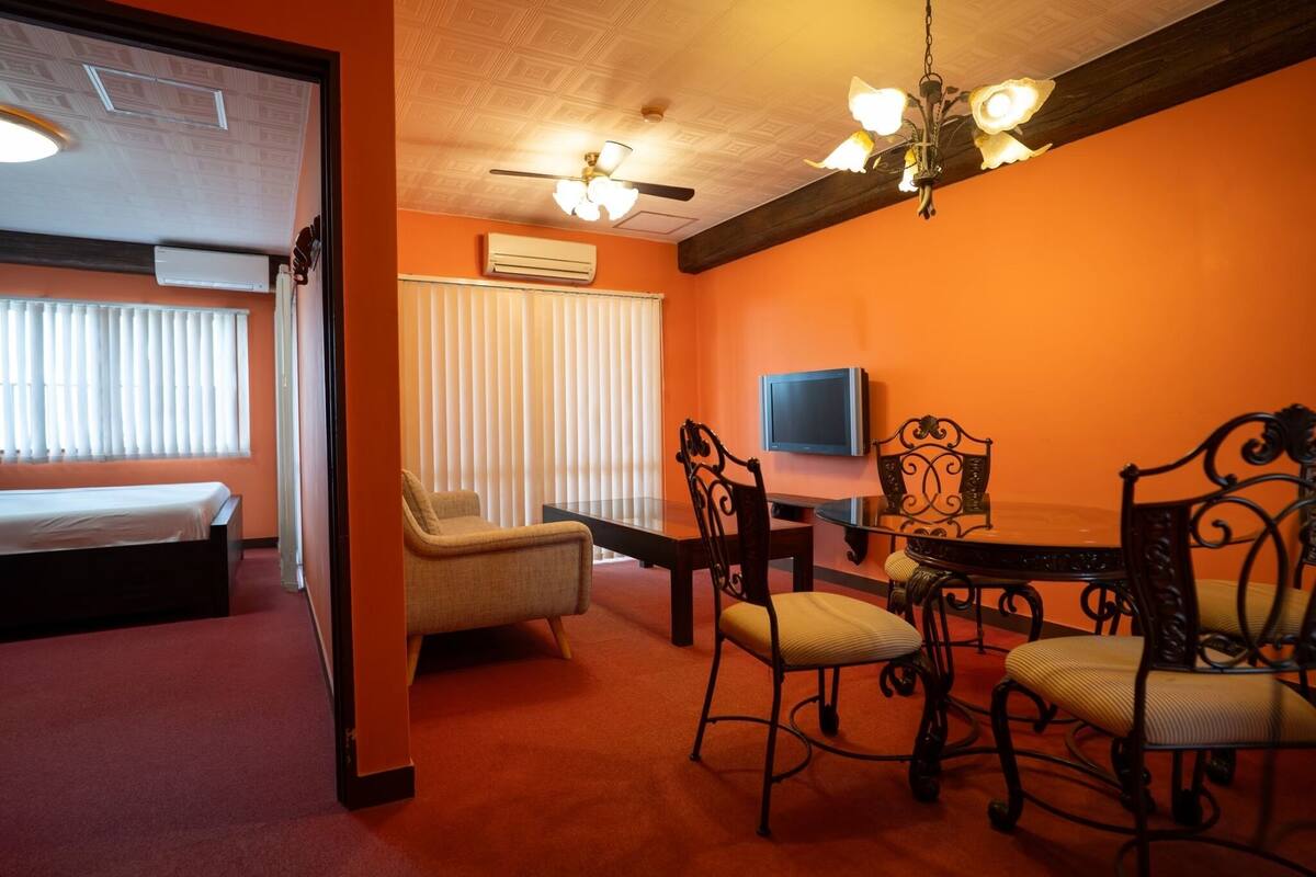 A room with a bed, a chair, a table, and a TV.