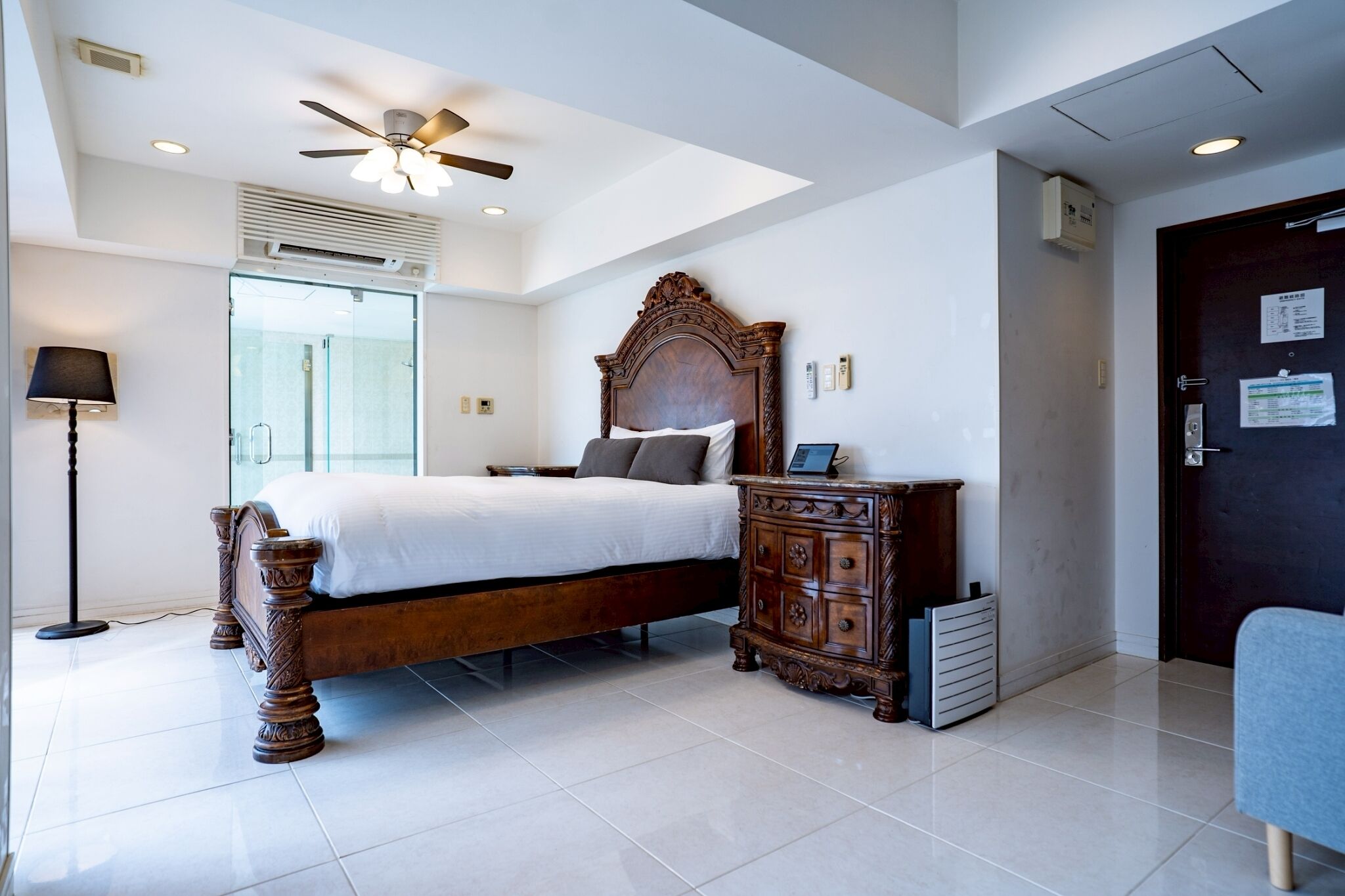 A bedroom with a wooden bed, a nightstand, a ceiling fan, a window, and a door.