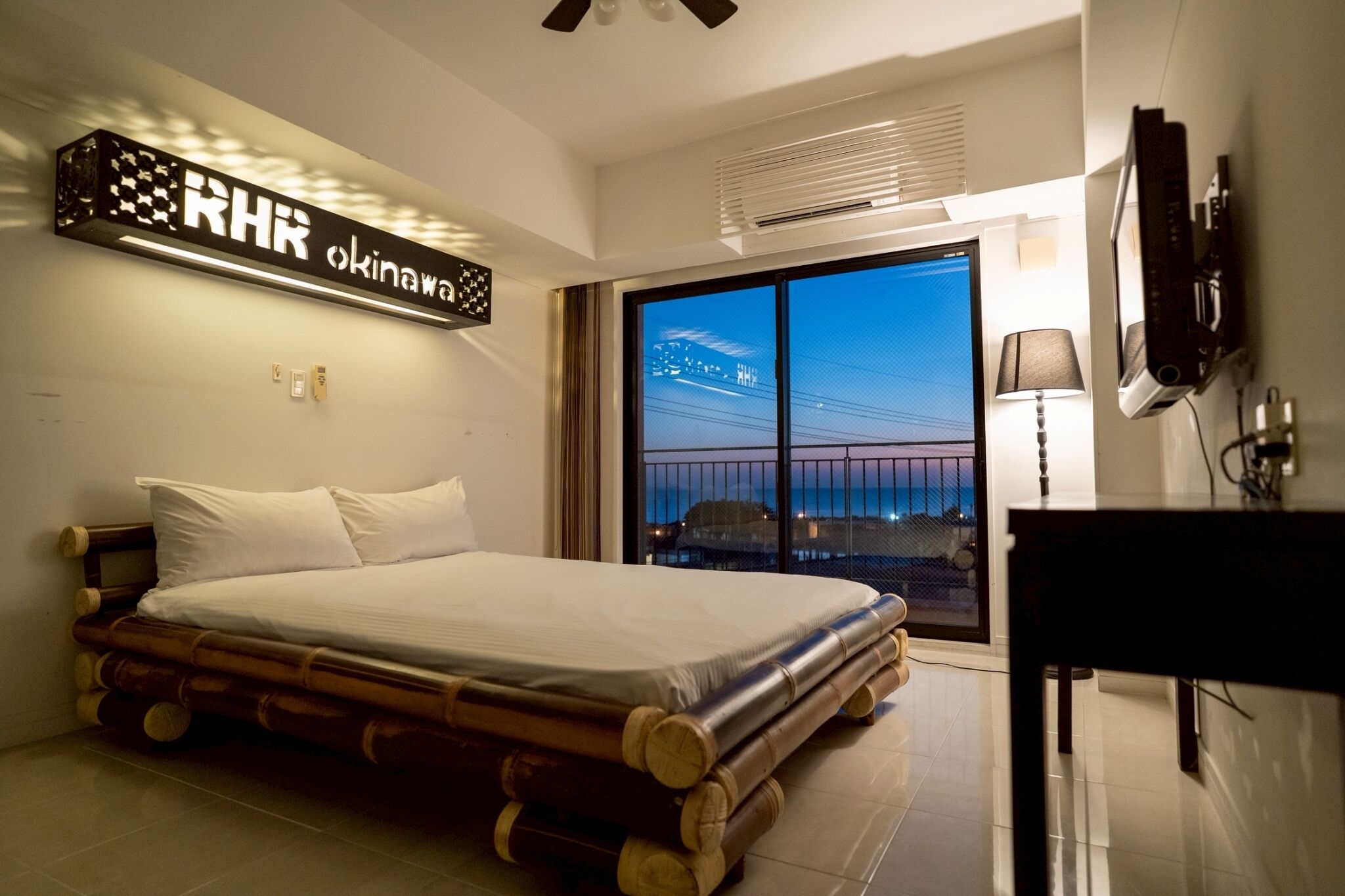 A hotel room with a bed, a TV, a desk, and a balcony with a view.
