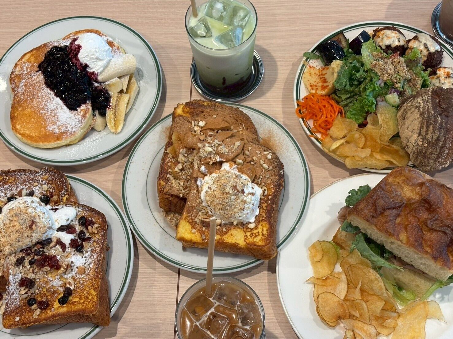 Une table garnie de divers aliments pour le petit-déjeuner, notamment des crêpes, des toasts, un sandwich et une salade.