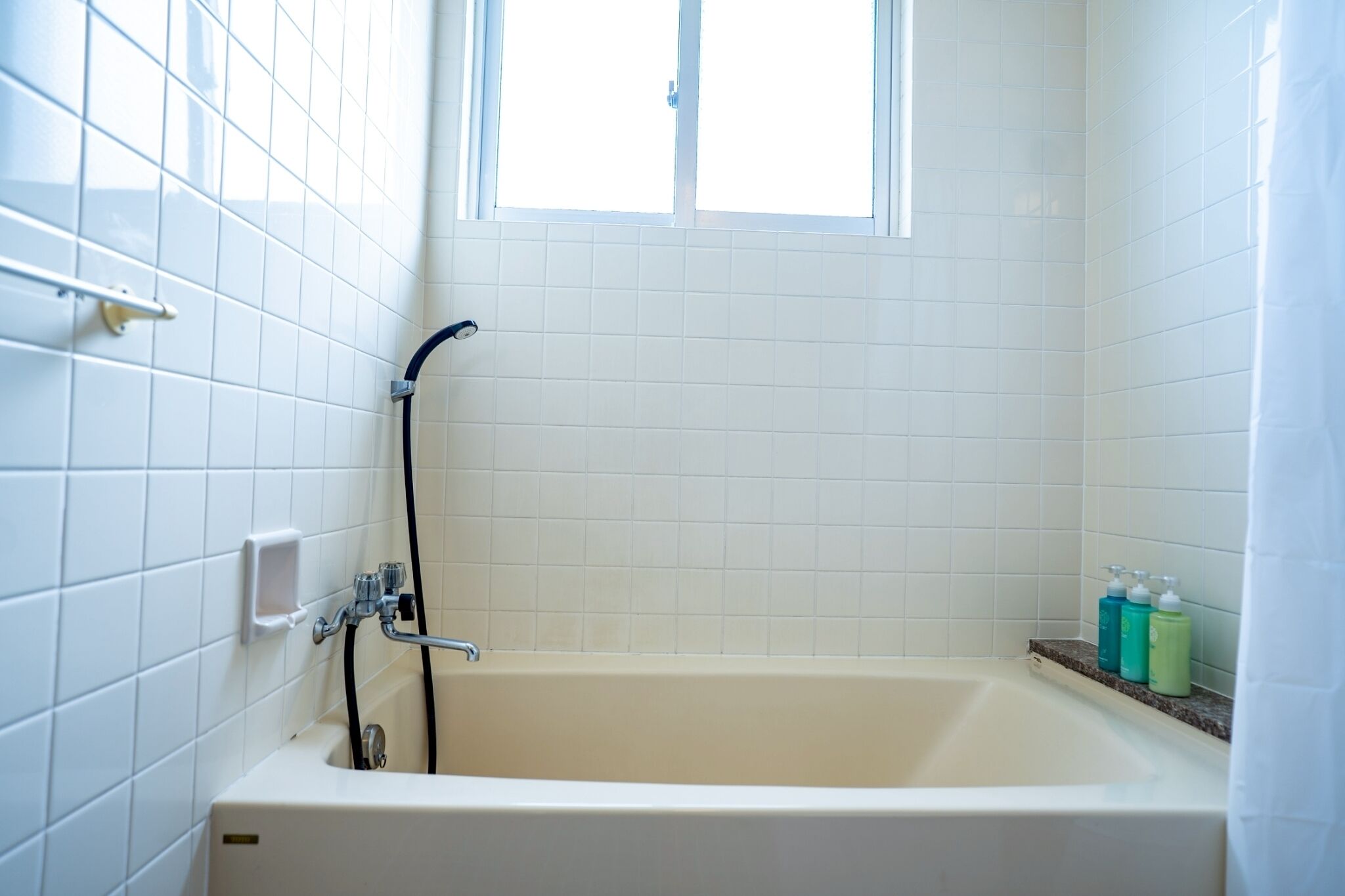 A bathroom with a bathtub, a window, and a shower.