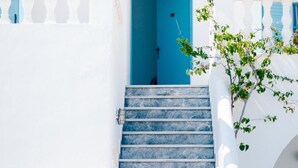 Un edificio blanco con una puerta azul y una escalera que lleva a un nivel superior.