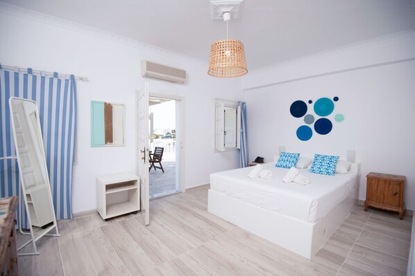 Un dormitorio con una cama grande, una mesita de noche de madera, un espejo, un armario y vistas al exterior.
