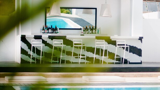 Un bar junto a la piscina con diseño moderno, que incluye una barra y una zona de estar.