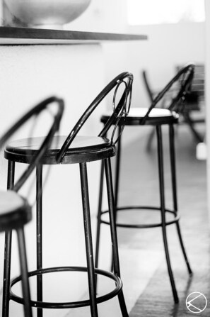 A close-up of two metal bar stools with curved backs and metal legs, positioned in a modern, minimalistic setting.