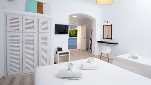 Habitación de hotel moderna con una cama, un escritorio, una silla, un televisor, un espejo y vistas al exterior.