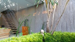 A modern interior with a staircase, a wooden bench, and a small statue. - Sandhya Villa (Canggu)