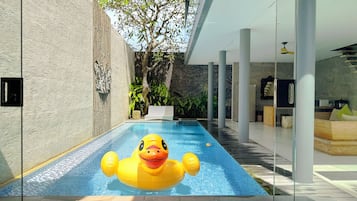 Relax by the pool surrounded by a glass wall and white columns.