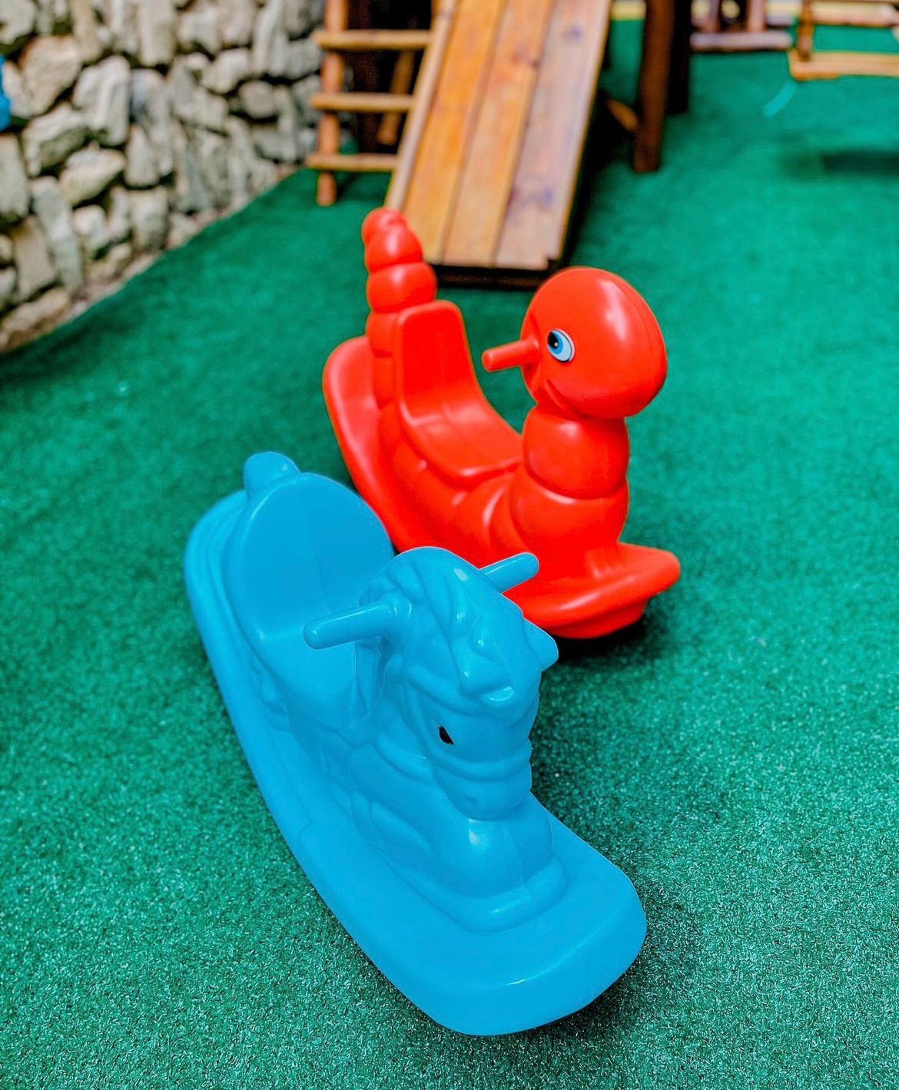 Two plastic toy boats on a green surface.