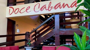 A spacious lobby with a staircase, wicker furniture, and a sign reading "Doce Cabana". - Pousada Doce Cabana (Ipojuca)