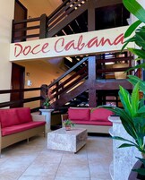 Un vestíbulo amplio con una escalera, muebles de mimbre y un cartel que dice "Doce Cabana".