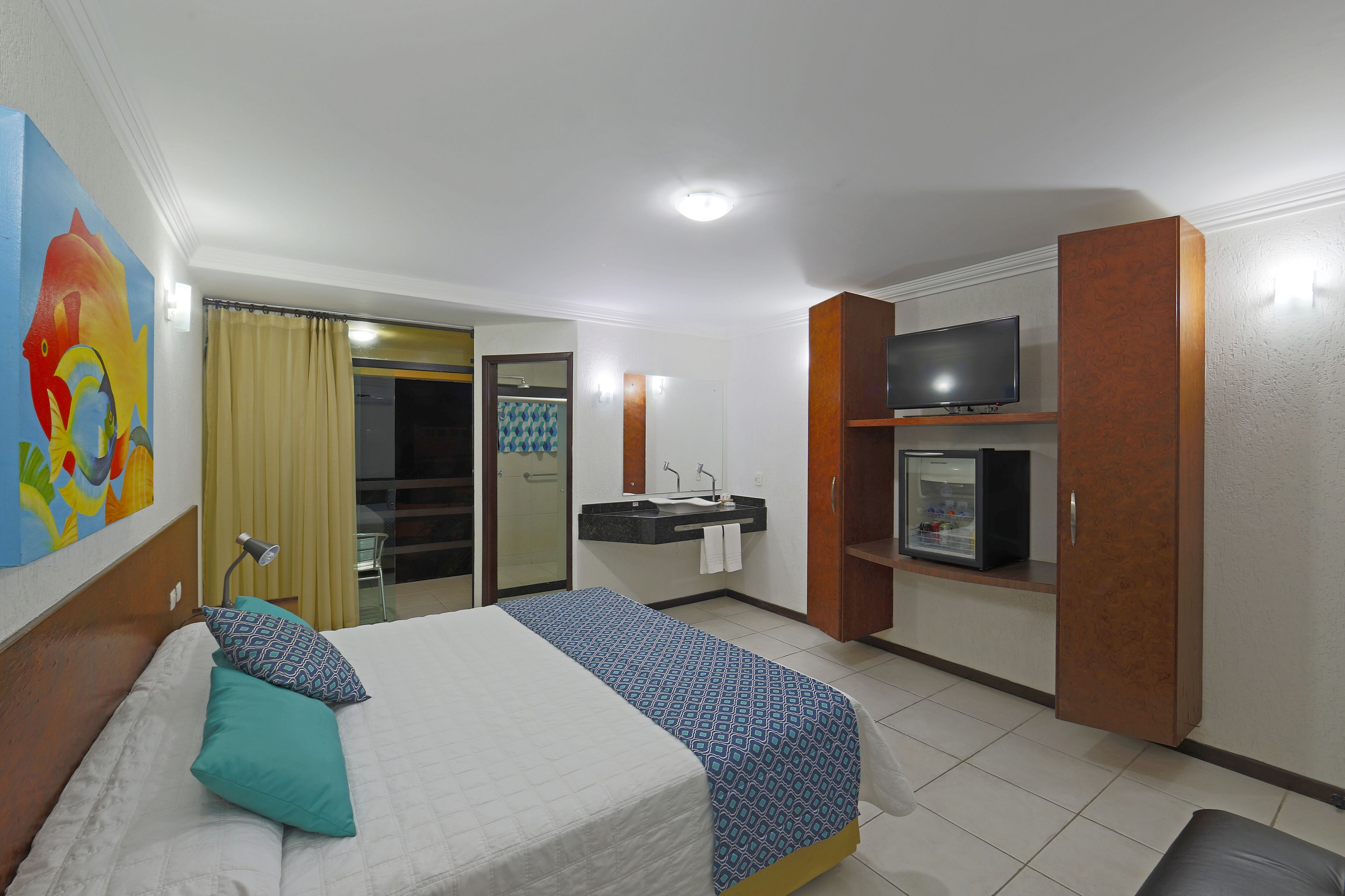 Une chambre d’hôtel équipée d’un lit, d’une télévision, d’une salle de bain et d’un mini-bar.