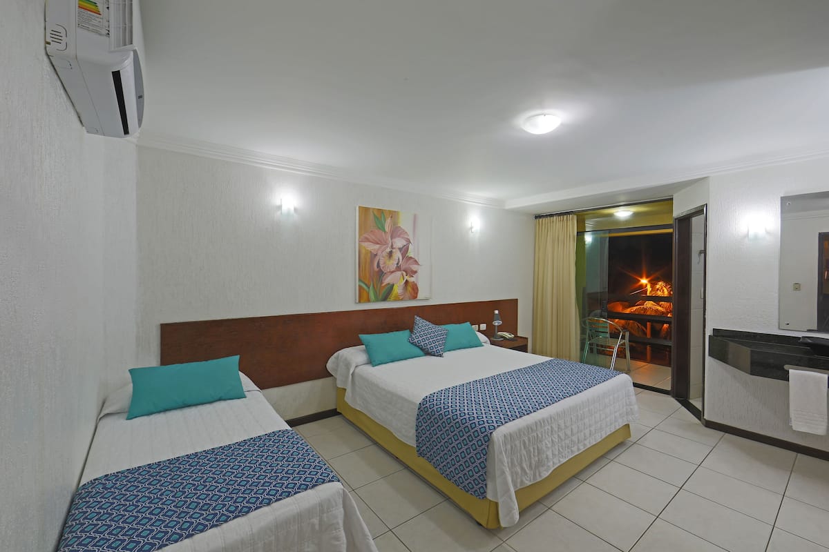 Quarto de hotel com duas camas, banheiro e vista para uma fogueira.