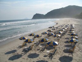 Arena blanca, sillas reclinables de playa, sombrillas