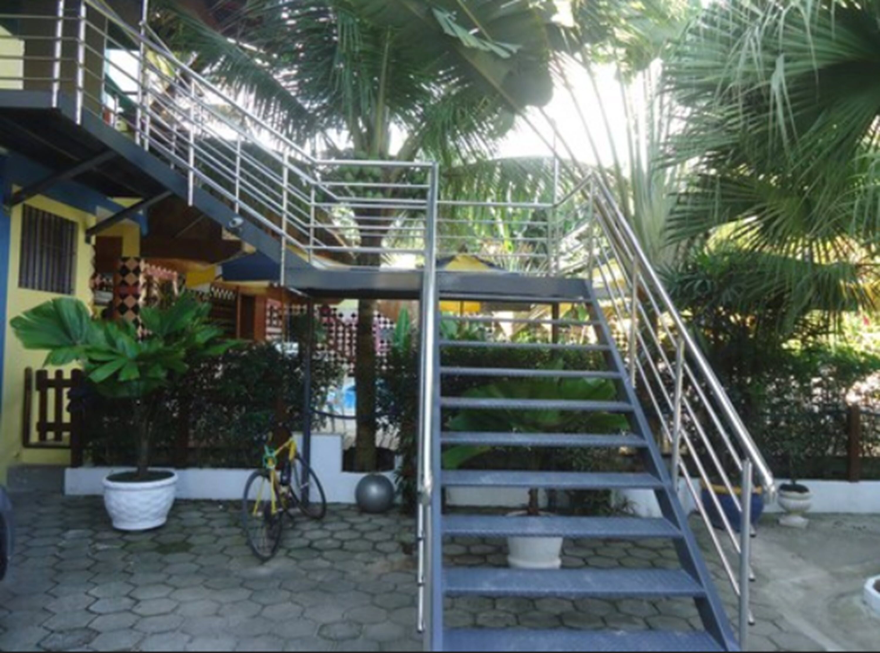 A staircase leading to a second floor, surrounded by potted plants and a bicycle.