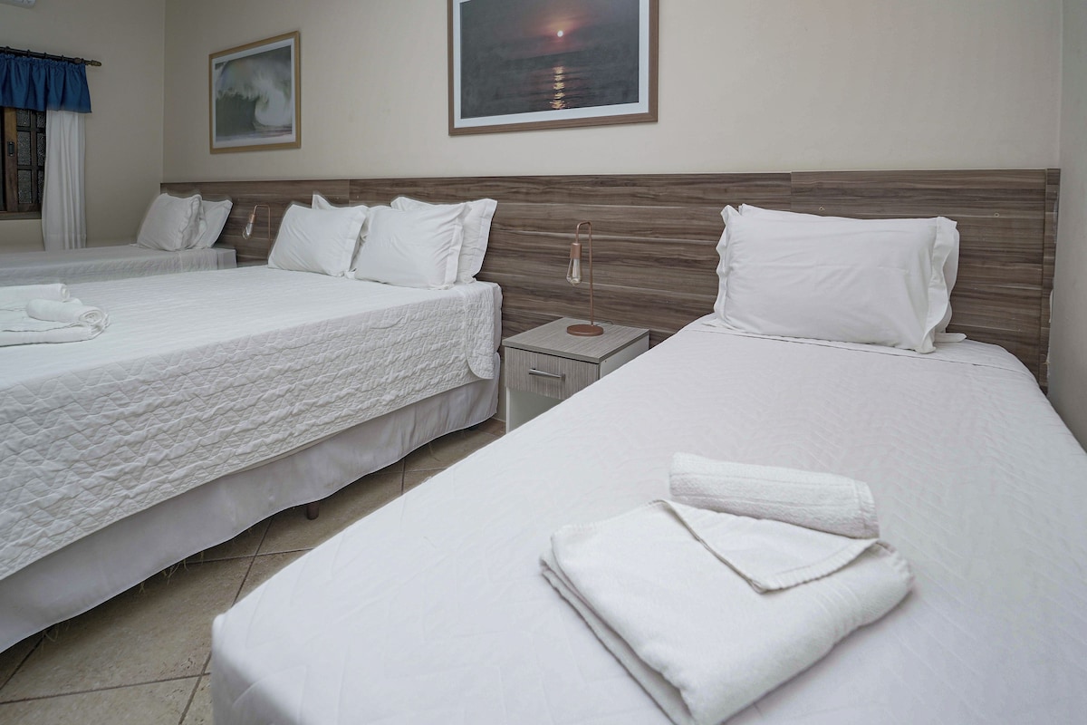 A hotel room with two beds, a nightstand, a lamp, and a painting on the wall.