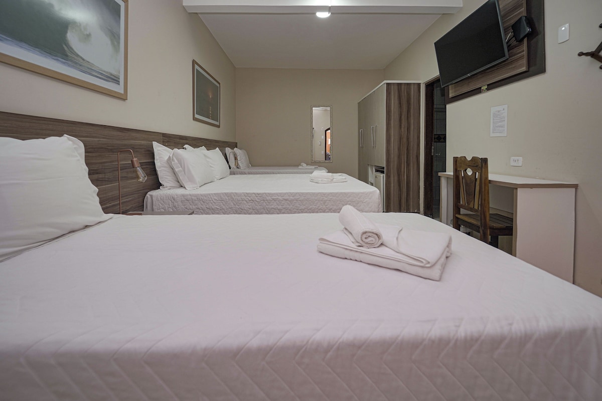 A hotel room with two beds, a TV, a mirror, and a desk.