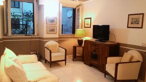 Una sala de estar con un sofá, televisor, lámpara y ventana con vistas al exterior.
