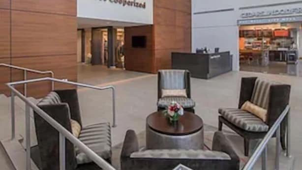 A spacious lobby with a high ceiling, a central seating area, and a visible restaurant in the background. - Cooper Hotel Conference Center & Spa (Dallas)
